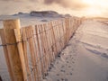 Wooden fence on a sand dune and animal footprints. Sunset sky in the background. Stunning nature scene. Dog`s bay, county Galway,