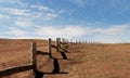 Wooden fence in steppe, blue sky with clouds. Royalty Free Stock Photo