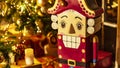 Wooden festive toy nutcracker on the background of a Christmas tree, gifts, lights, candles. Christmas and New Year interior Royalty Free Stock Photo
