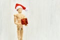 Wooden figure - art mannequin with red Santa hat with gift box Royalty Free Stock Photo