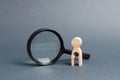 A wooden figure with a baby-shaped void stands near a magnifying glass. concept of infertility and women and the inability to have