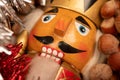 Wooden figure in the form of a soldier for chopping nuts surrounded by colored tinsel and hazelnuts in bulk. New year and Royalty Free Stock Photo