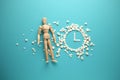 Wooden figure of man on background of clock made of pills. Postpone treatment until later. Neglected, progressive diseases