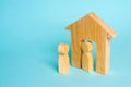 A wooden figure of a man meets a guest on a blue background. Wooden house. The concept of an apartment house, real estate. Royalty Free Stock Photo