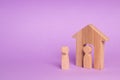 A wooden figure of a man meets a guest on a purple background. Wooden house. The concept of an apartment house, real estate. Royalty Free Stock Photo