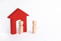 A wooden figure of a man meets a guest on a white background. Red house. The concept of an apartment house, real estate. Royalty Free Stock Photo