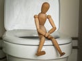 Wooden figure of a man sitting on the toilet in the toilet, health problems, constipation, diarrhea, abdominal