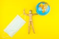 Wooden figure mannequin carrying planet earth globe over head on a yellow background Royalty Free Stock Photo