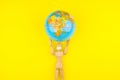 Wooden figure mannequin carrying planet earth globe over head on a yellow background Royalty Free Stock Photo