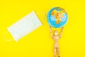 Wooden figure mannequin carrying planet earth globe over head on a yellow background Royalty Free Stock Photo