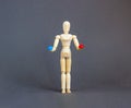 Wooden figure of a mannequin holding a red pill and blue pill on a grey background. Coronavirus, pandemic and epidemic concept. Royalty Free Stock Photo