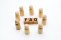 Wooden figures as business team in circle around acronym FAQ Frequently Asked Questions