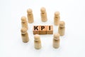 Wooden figures as business team in circle around acronym KPI Key Performance Indicator