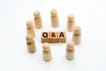 Wooden figures as business team in circle around acronym Q&A Questions and Answers