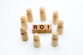 Wooden figures as business team in circle around acronym ROI Return On Investment
