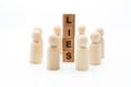 Wooden figures as business team in circle around word LIES