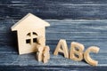 Wooden figures of children stand in a row from small to large near the letters of the English alphabet abc.