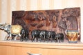Wooden figures of elephants stand against the background of a wooden panel made by an African artist Royalty Free Stock Photo
