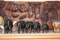 Wooden figures of elephants stand against the background of a wooden panel made by an African artist Royalty Free Stock Photo