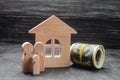 Wooden figures of the family stand near a wooden house and collapsed money. Buying and selling a house. Good life, moving