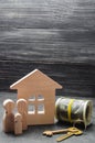 The wooden figures of the family stand near a wooden house, keys and collapsed money. Buying and selling a house. Good life