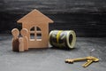 The wooden figures of the family stand near a wooden house, keys and money. Buying and selling a house. Good life, moving to new a Royalty Free Stock Photo