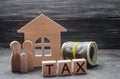 Wooden figures of the family stand near a wooden house and money. Property tax. Payment of taxes to the state. Law-abiding citizen Royalty Free Stock Photo