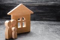 Wooden figures of the family stand near a wooden house. The concept of finding a new home, moving. A healthy strong family
