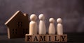 Wooden figures family standing on Wooden cube that writes the word family in front of a wooden house. The concept of Protection Royalty Free Stock Photo