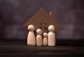 Wooden figures family standing in front of a wooden house. The concept of Protection and safety, Home Security, property insurance Royalty Free Stock Photo