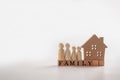 Wooden figures family standing beside a wooden house on a wooden cube that writes the word family. The concept of Protection and