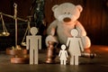 Wooden figures of family with teddy bear and gavel in a courtroom. Divorce and alimony concept Royalty Free Stock Photo