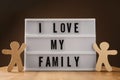 Wooden figures and lightbox with phrase I Love My Family on table