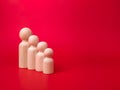 Wooden figures lined up according to their respective heights on red background