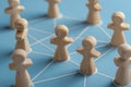 Conceptual wooden figures connected by strings on blue background symbolizing teamwork and social network collaboration in Royalty Free Stock Photo