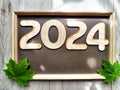 Wooden figures and numbers of the new year 2024 with frame and green maple leaves. Celebration with simbol Canada