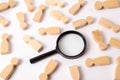 Wooden figures of people lie around a magnifying glass on a white background. The concept of the search for people and workers