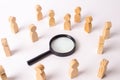Wooden figures of people stand around the magnifying glass and look to the center. The concept of the search for people and worker Royalty Free Stock Photo
