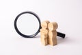 Wooden figures of people stand near the magnifying glass. The family is looking for something. The concept of housing search.