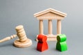 Wooden figures of people standing near the judge`s gavel. Litigation. Business rivals. Conflict of interest. Law and justice. The Royalty Free Stock Photo