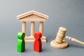 Wooden figures of people standing near the judge`s gavel. Litigation. Business rivals. Conflict of interest. Law and justice. The Royalty Free Stock Photo
