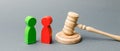 Wooden figures of people standing near the judge`s gavel. Litigation. Business rivals. Conflict of interest. Law and justice. The Royalty Free Stock Photo