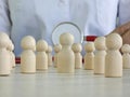 Wooden figures of people and a stethoscope in the hands of a therapist