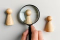 Wooden figures of people under magnifying glass on gray background. Concept of personnel recruitment and selection Royalty Free Stock Photo
