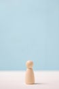 Wooden figurine on a blue background. The concept of loneliness