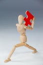 Wooden figurine holding a red puzzle piece