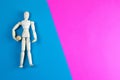 Wooden figurine of a man with a ball on a blue and pink background with clear space for text