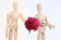 Wooden figurine man holding rose to lover. Royalty Free Stock Photo