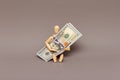 Wooden figurine of a man holding a stack of hundred dollar bills. Royalty Free Stock Photo