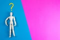 Wooden figurine of a man with question mark on a blue and pink background with clear space for text